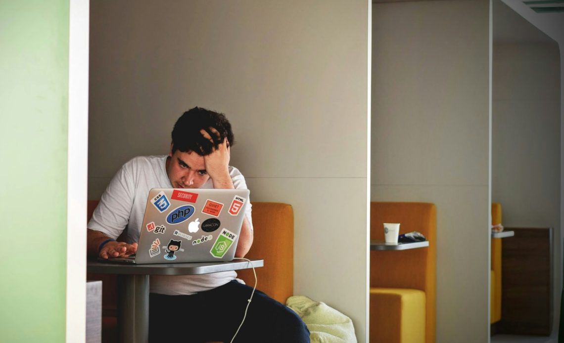 man wearing white top using MacBook