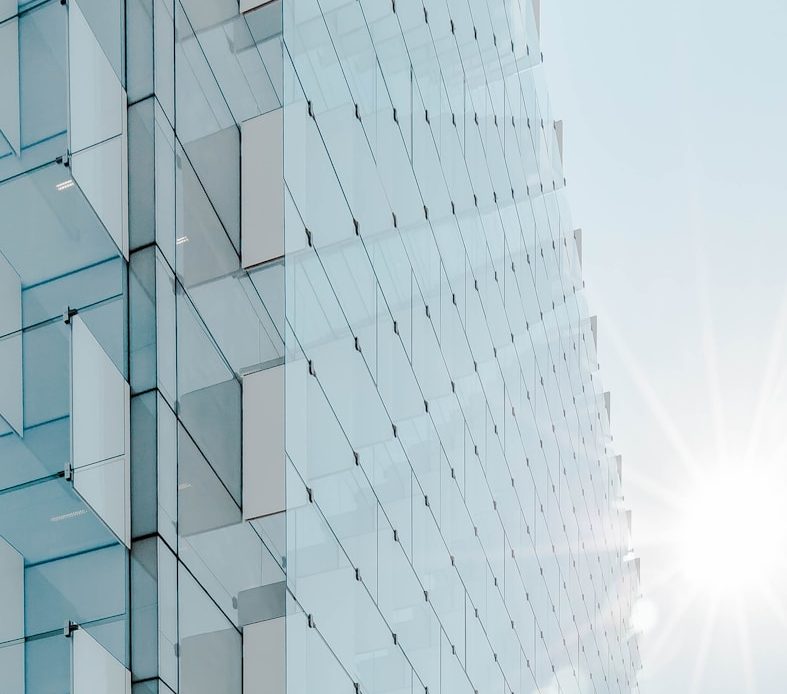 glass panel high-rise building under blue sky with sun raise