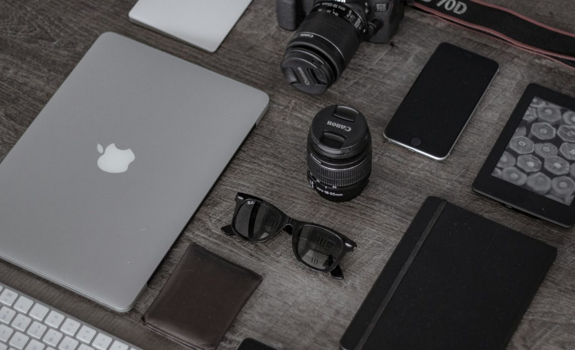 iPad near sunglasses, wallet, and DSLR camera