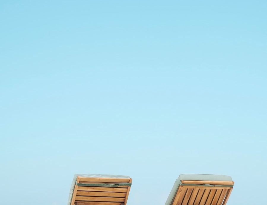 two brown wooden outdoor chaise loungers on beach