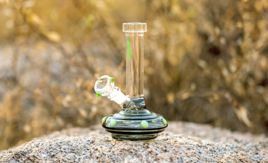 clear glass water bong on gray rock