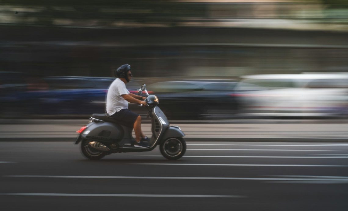 man in white shirt and black pants riding on black motor scooter