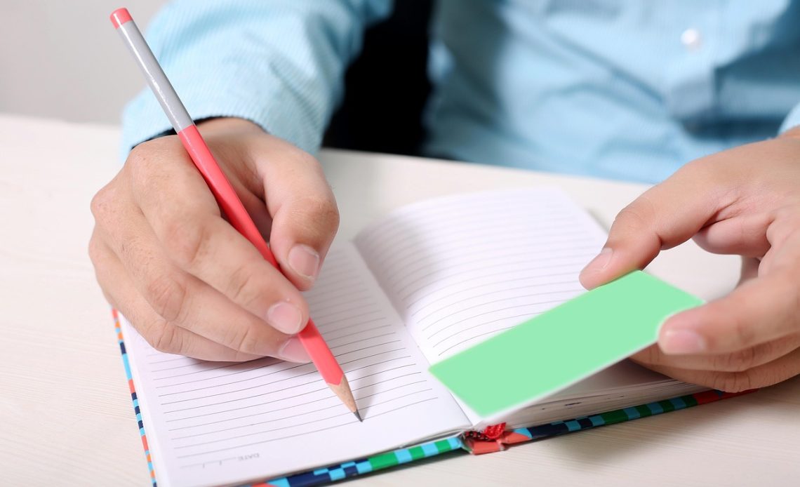 Man schrijft persoonlijke doelen op in een notitieboek aan zijn bureau