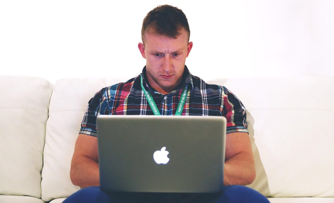 Man werkt geconcentreerd op laptop aan zijn bureau thuis