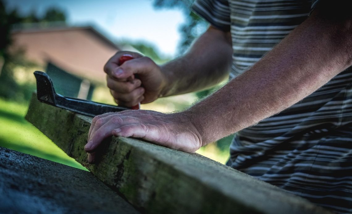 Man die werkt in een houten werkplaats met gereedschap op tafel