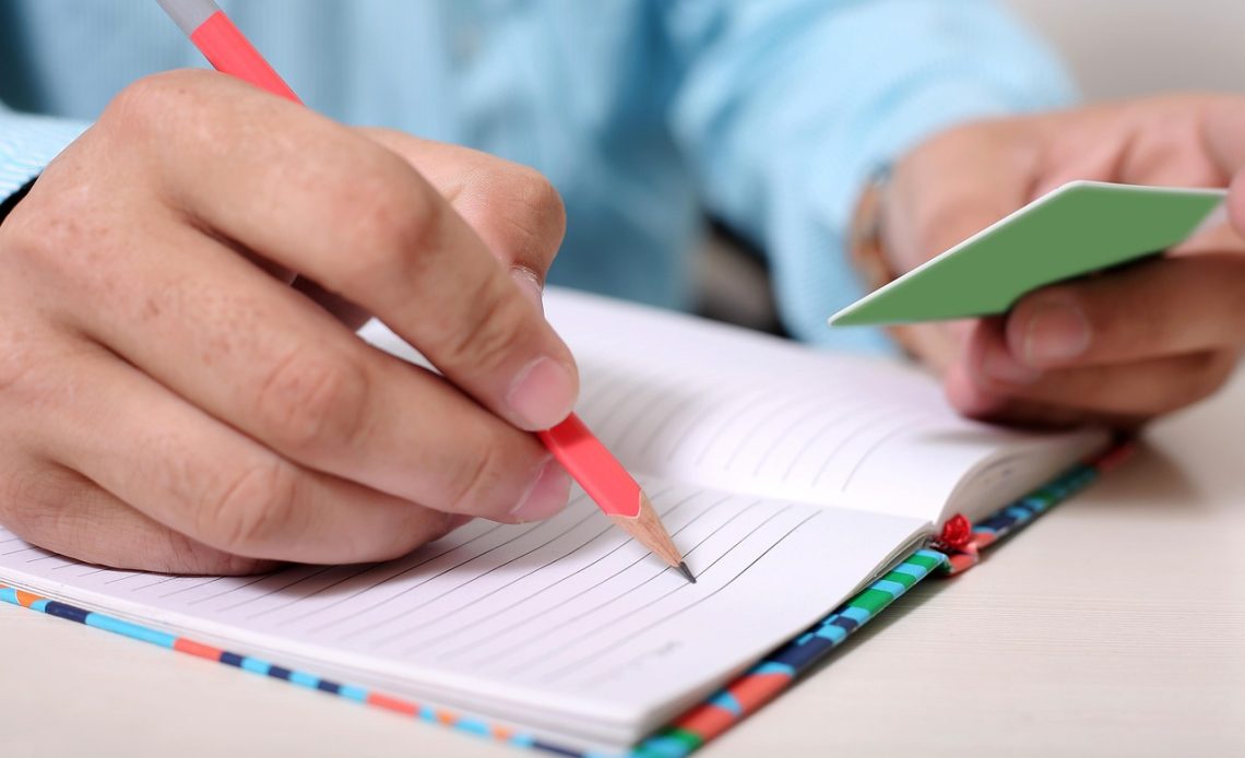 Man die zijn persoonlijke doelen en prestatie-indicatoren opschrijft in een notitieboek aan zijn bureau