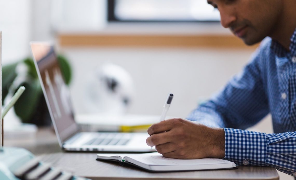 Man schrijft persoonlijke doelen op in een notitieboek aan bureau