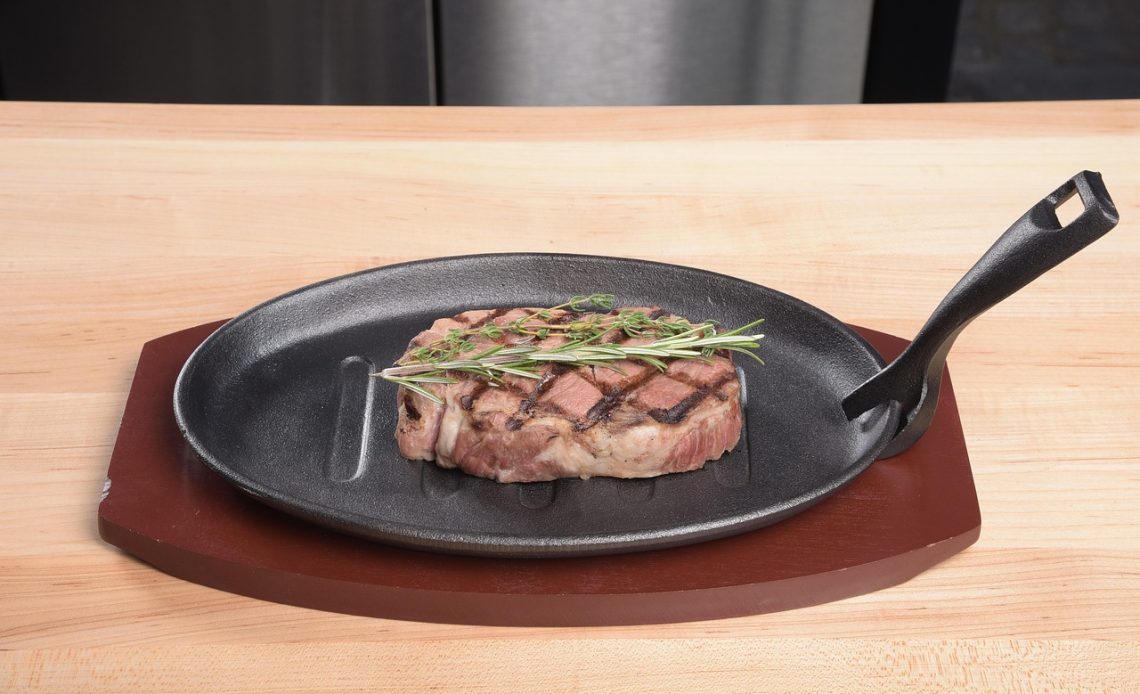 Geroosterde bloemkoolsteak in een koekenpan met kruiden