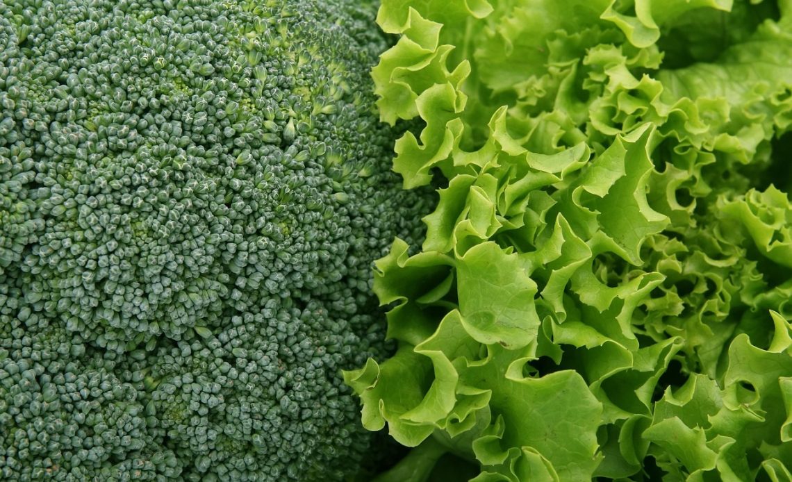 Vers gesneden broccoliroosjes op een houten snijplank, klaar om te stomen of koken